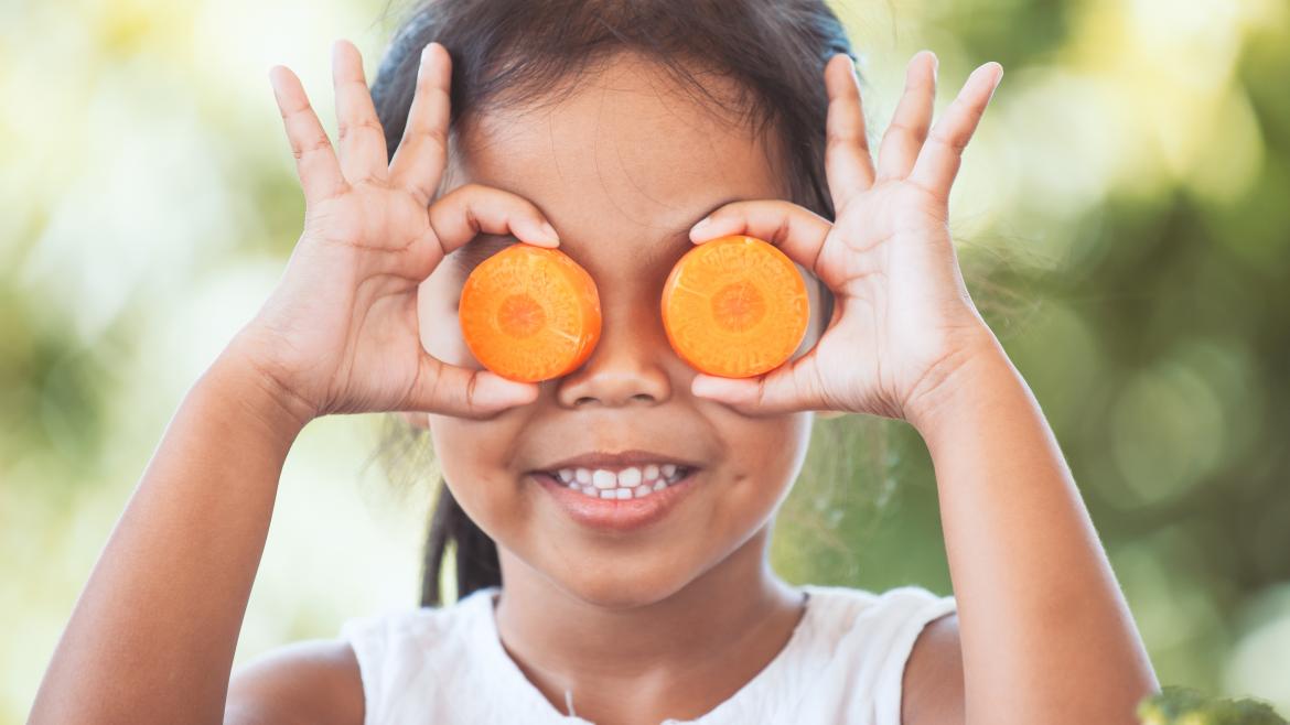 Kind hält sich Möhrenschieben vor die Augen