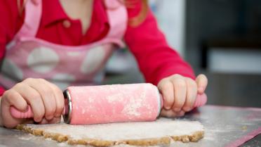 Kind rollt Plätzchenteig aus