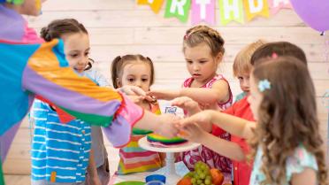 Kinder in der Kita sethen um eine Torte