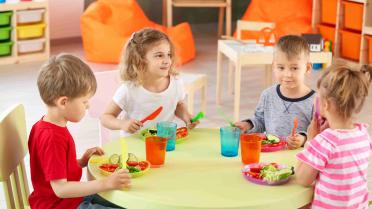 Kinder sitzen in der Kita gemeinsam am Tisch.
