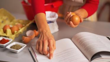 Frau liest Rezept in Buch