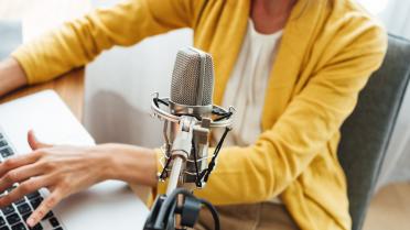 Podcastmikrofon vor Frau. Frau im Hintergrund.