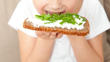 Kind beißt in Brot mit Schnittlauch
