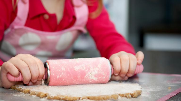 Kind rollt Plätzchenteig aus