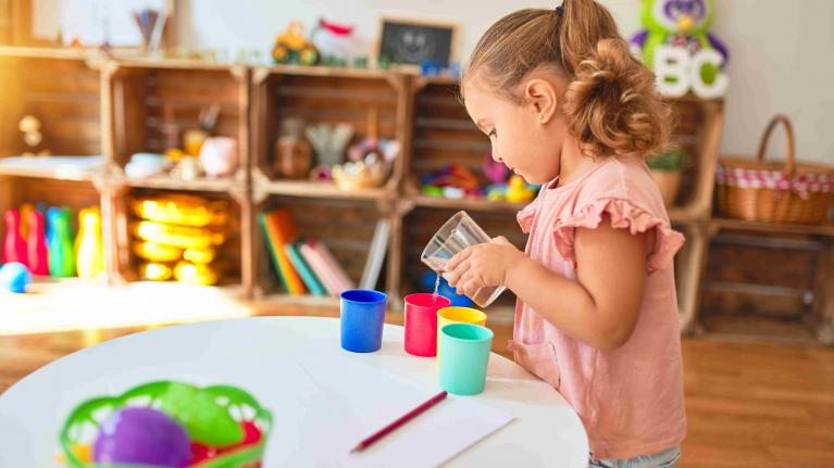 Kind experimentiert in Kita mit Wasser