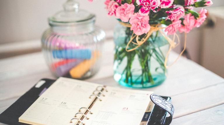 Terminplaner auf Tisch mit Blumen im Hintergrund