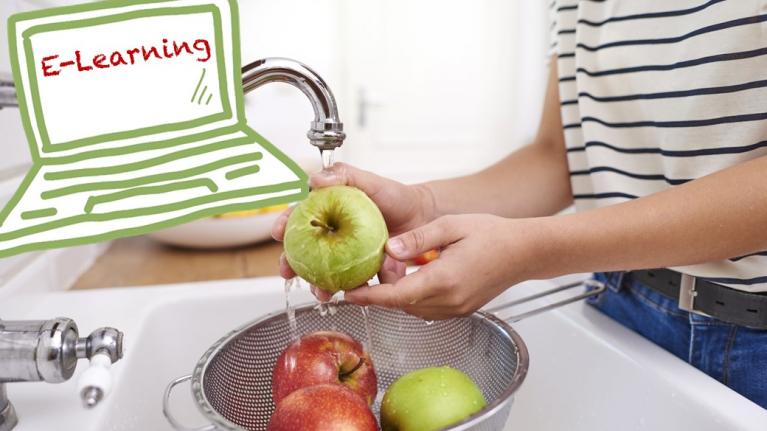 Frau wäscht Tomaten im Waschbecken über einem Haarsieb. Das Gexicht der Frau ist nicht zu sehen, sondern nur die Hände. Sie trägt eine Jeans und ein weiß-schwarz gestreiftes T-Shirt.