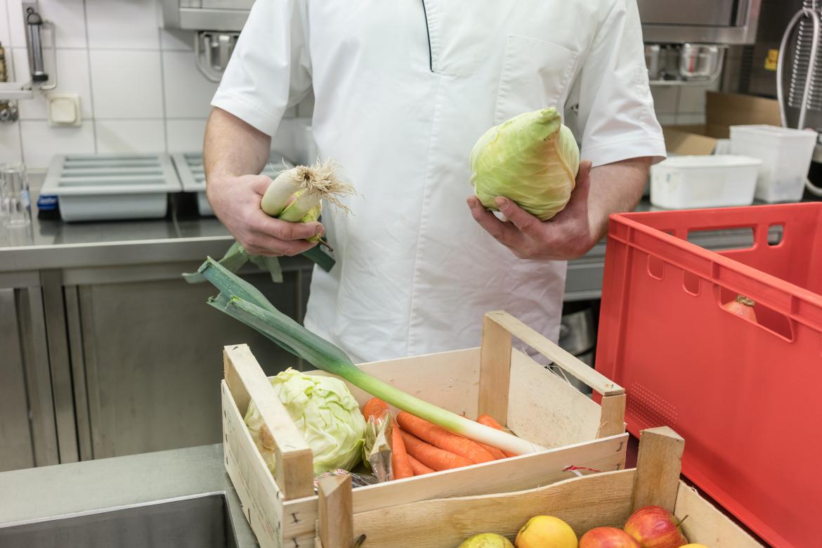 Koch hält Lauch und Spitzkohl in der Hand