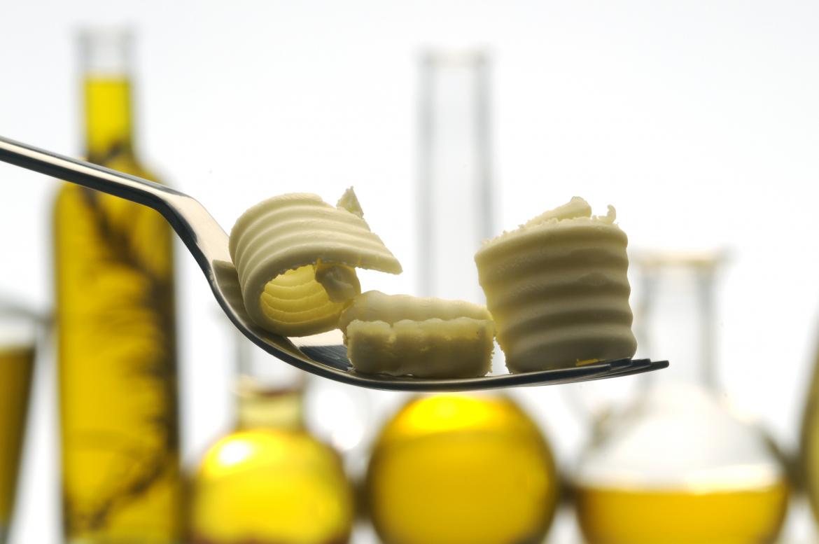 Butter auf einer Gabel, im Hintergrund Öl