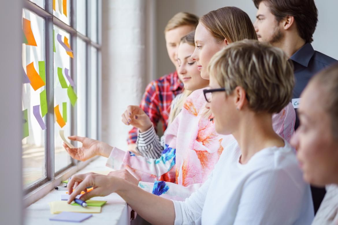 Workshopgruppe klebt bunte Klebezettel an ein Fenster