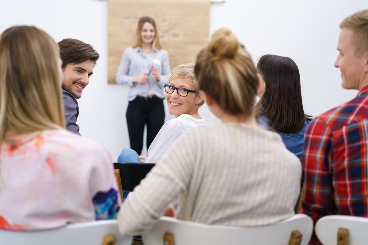 Vortrag in einem Workshop Teilnehmer schauen lächelnd auf eine Teilnehmerin