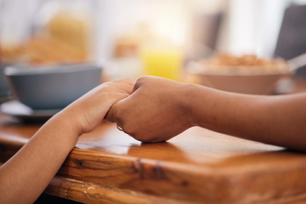 Kleine Hand hält große Hand am Tisch