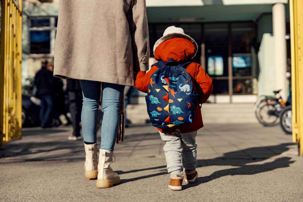 Kind läuft an der Hand mit Rucksack auf in die Kita