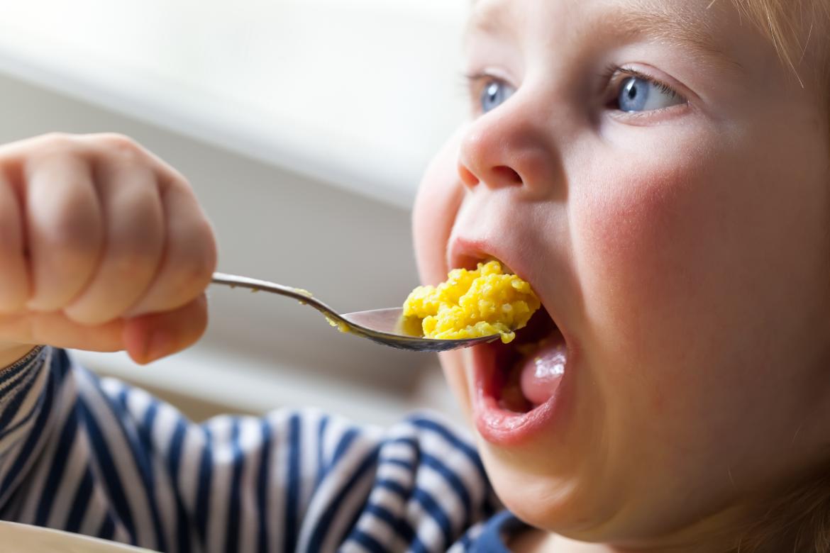 Kleindkind isst gelben Reis von einem Löffel