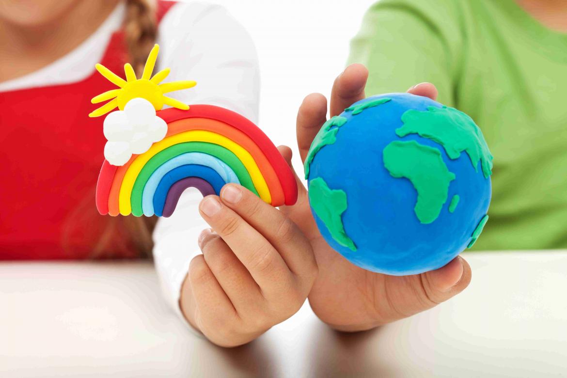 Regenbogen und Welt aus Knetgummi in der Hand von Kindern