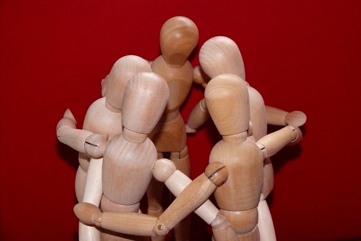 Holzfiguren/  Gliederfiguren ohne Gesuchter bilden einen Kreis und umarmen sich
