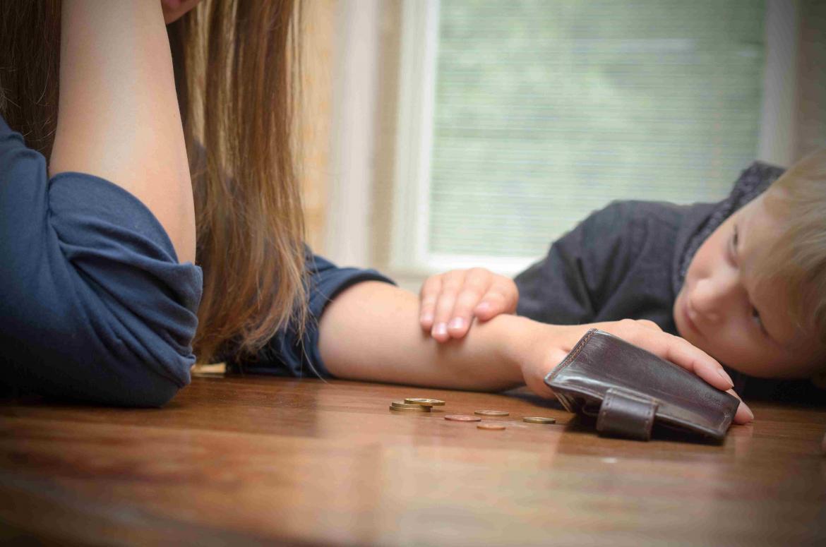 Mutter und Kind am Tisch mit Centstücken aus dem Portemonnaie
