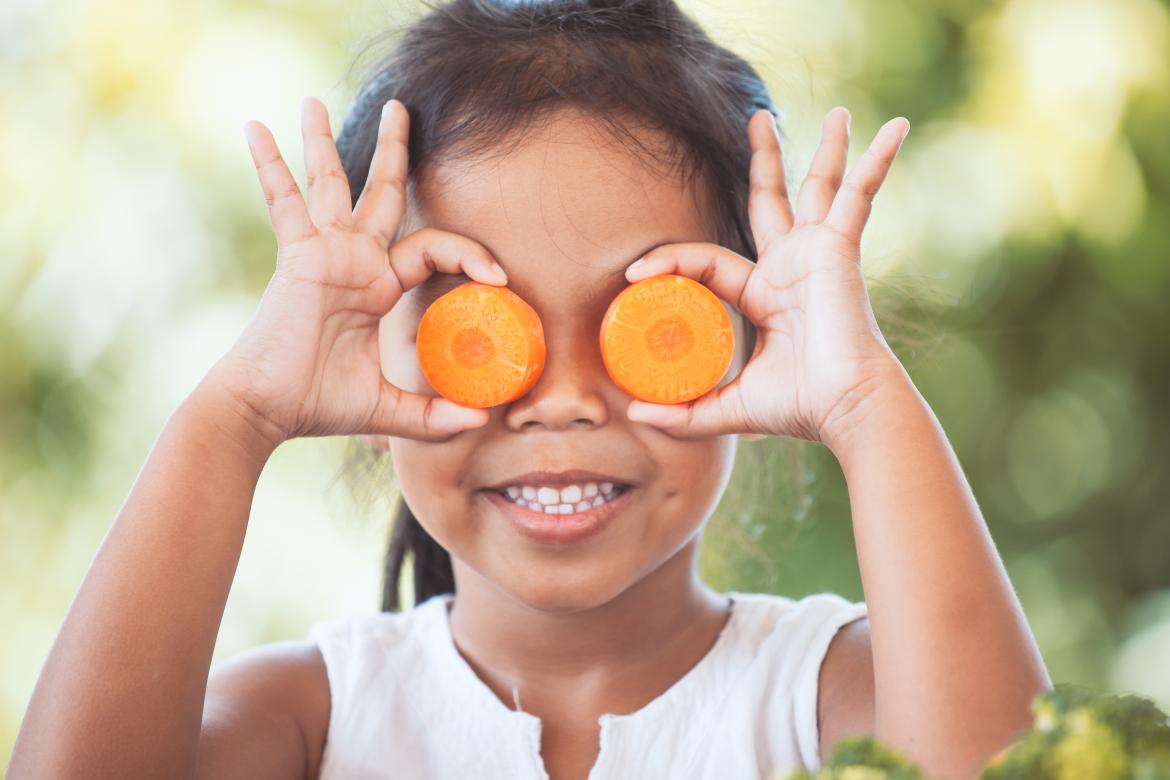 Kind hält sich Möhrenschieben vor die Augen