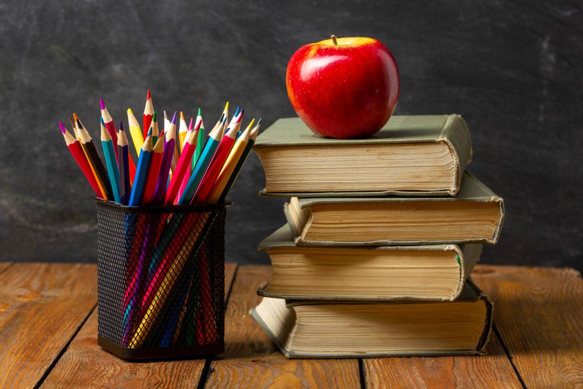 Stifte Apfel und Bücher auf Tisch