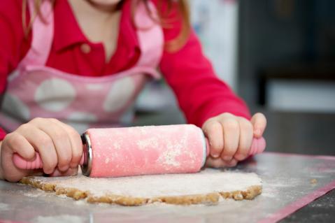 Kind rollt Plätzchenteig aus