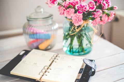 Terminplaner auf Tisch mit Blumen im Hintergrund