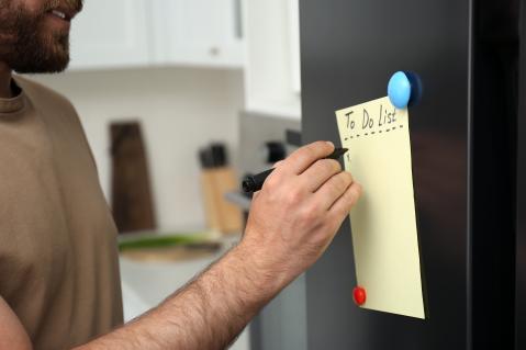 Mann schreibt eine To Do Liste. Er ist nur halb im Bild zu sehen.