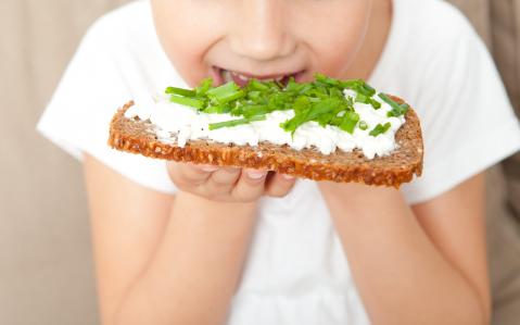 Kind beißt in Brot mit Schnittlauch